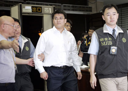 Chao Chien-ming, a doctor married to Taiwan President Chen Shui-bian's daughter, is escorted by Bureau of Investigation agents in Taipei May 24, 2006. Chao and four members of Chen's family were questioned on Wednesday by Bureau of Investigation agents probing a snowballing insider trading scandal.