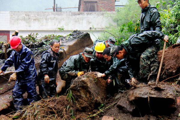 Rescuers examine a rock before they move it to rescue people buried underneath after a landslide in a village in Zhaotong, Yunnan province, on Friday. 5 dead, 4 injured in SW China landslide