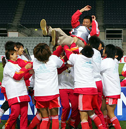 China's soccer players throw their coach Ma Liangxing up in the air as they celebrate their win over Australia in their Women's Asian Cup final soccer match in Adelaide July 30, 2006.