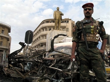 An Iraqi soldier stands by a car bomb wreck in front of a monument to Marouf al-Risafi, Iraqi poet, in central Baghdad, Iraq, Monday, March 26, 2007. Two people were killed and four were wounded in the bombing. (AP