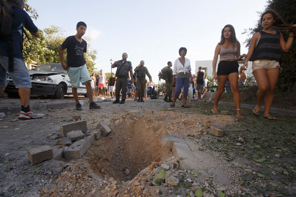 Israelis look at the crater caused by the impact of a rocket fired from Lebanon in Gesher Haziv, a kibbutz in northern Israel, on Thursday. Israel targets Palestinian group